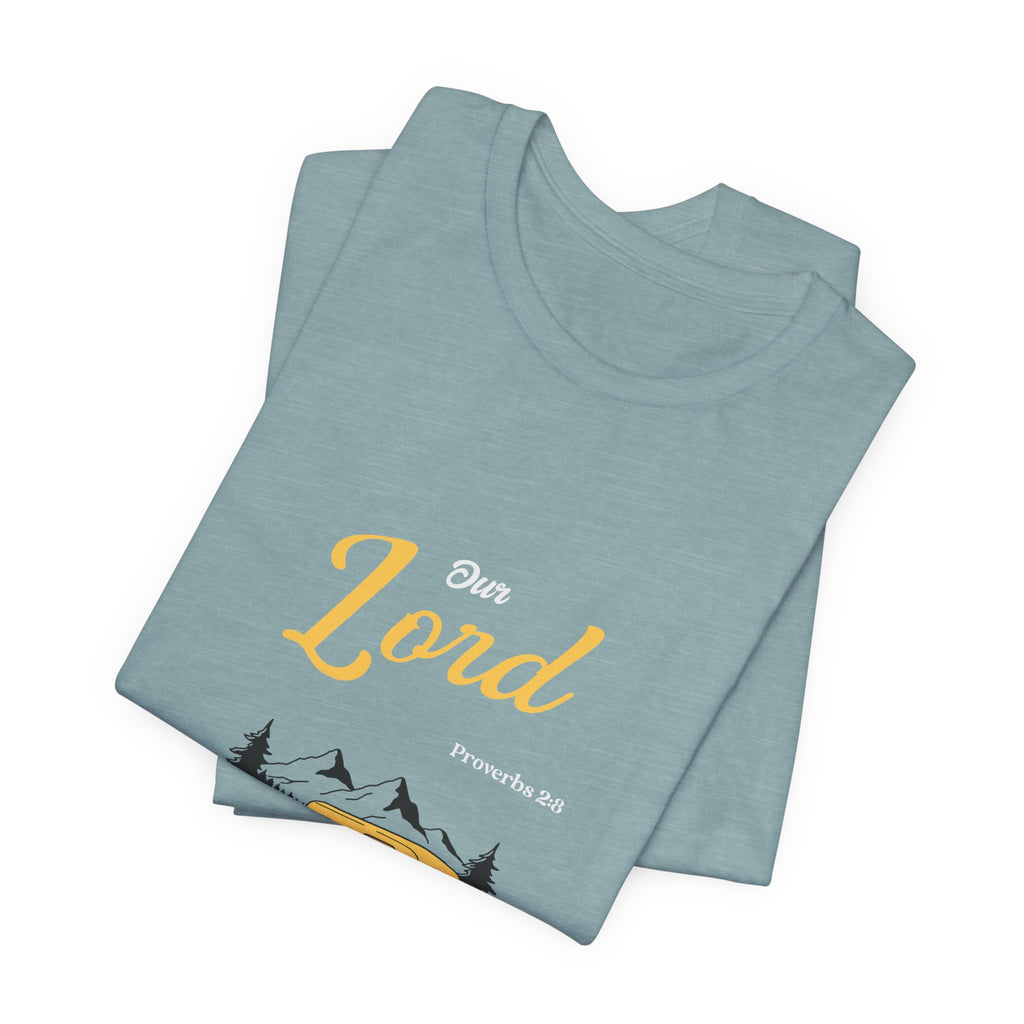Folded light blue t-shirt with 'Our Lord' text and mountain design on a white background