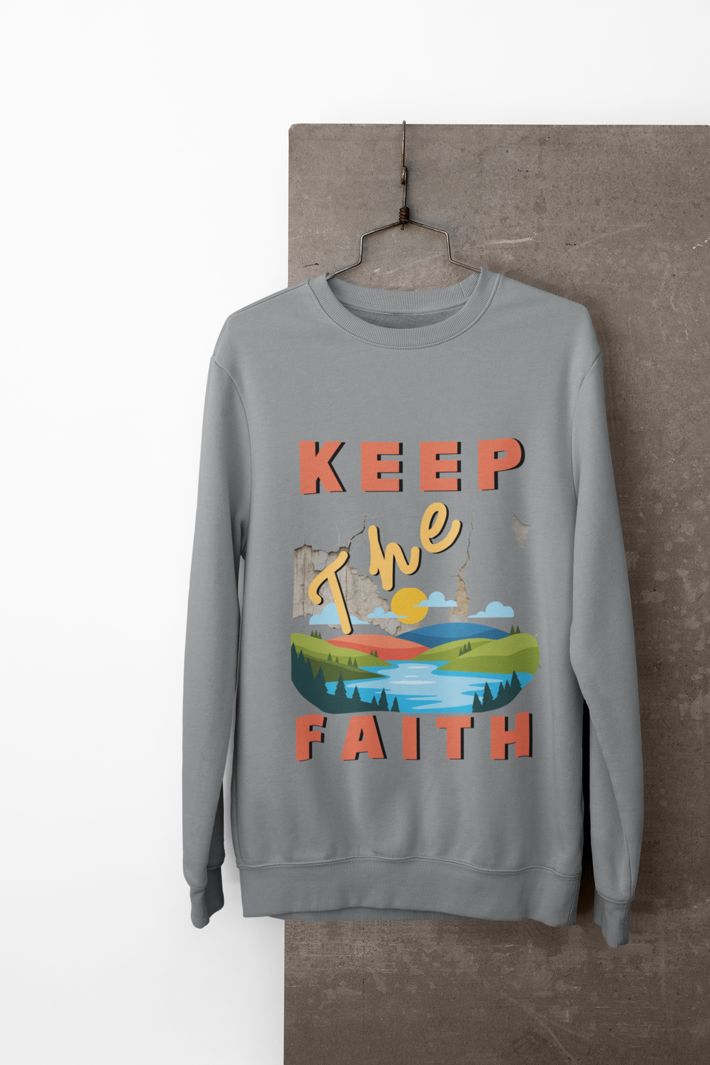 Gray sweatshirt with 'Keep The Faith' text and landscape graphic on a hanger.
