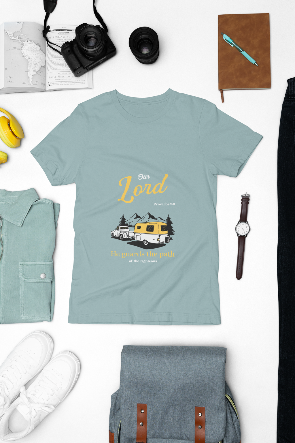 Light blue t-shirt with graphic design on a white surface with accessories around