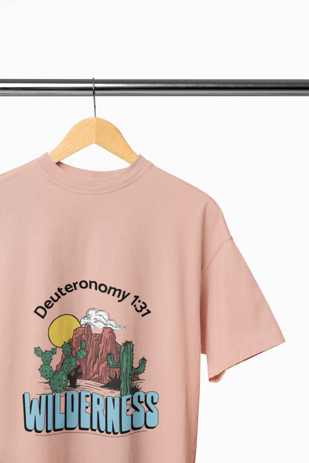 peach t-shirt with desert graphic and text on a hanger against a white background