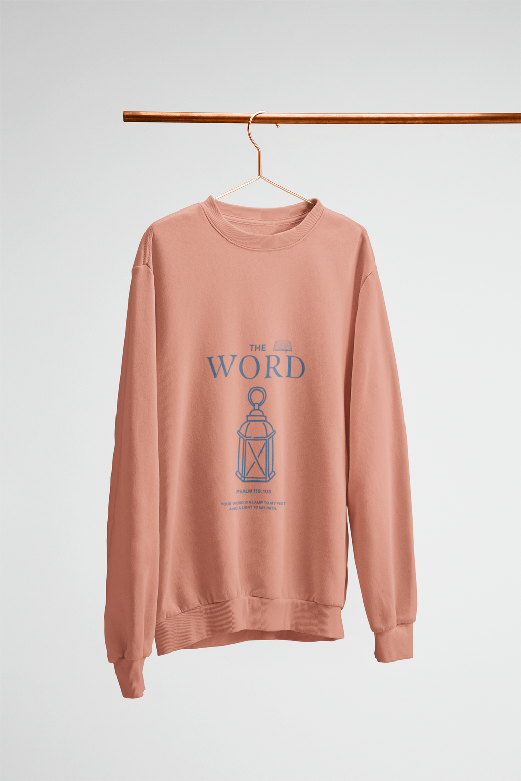 peach sweatshirt with 'The Word' graphic on a hanger against a white background