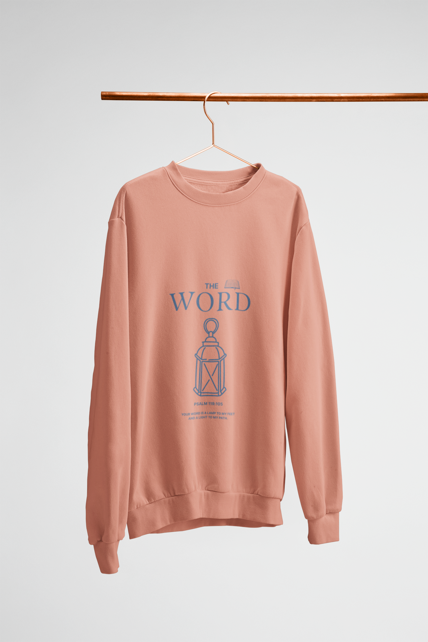 peach sweatshirt with 'The Word' graphic on a hanger against a white background