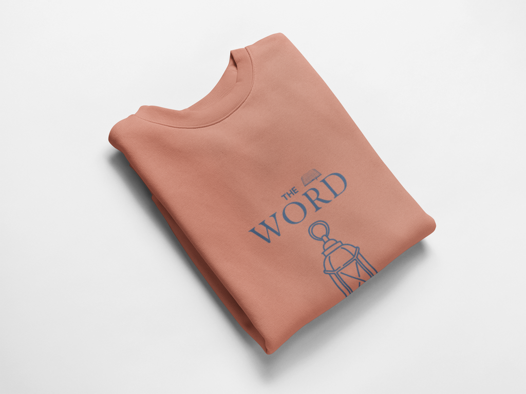 Folded peach sweatshirt with 'The Word' design on a light gray background