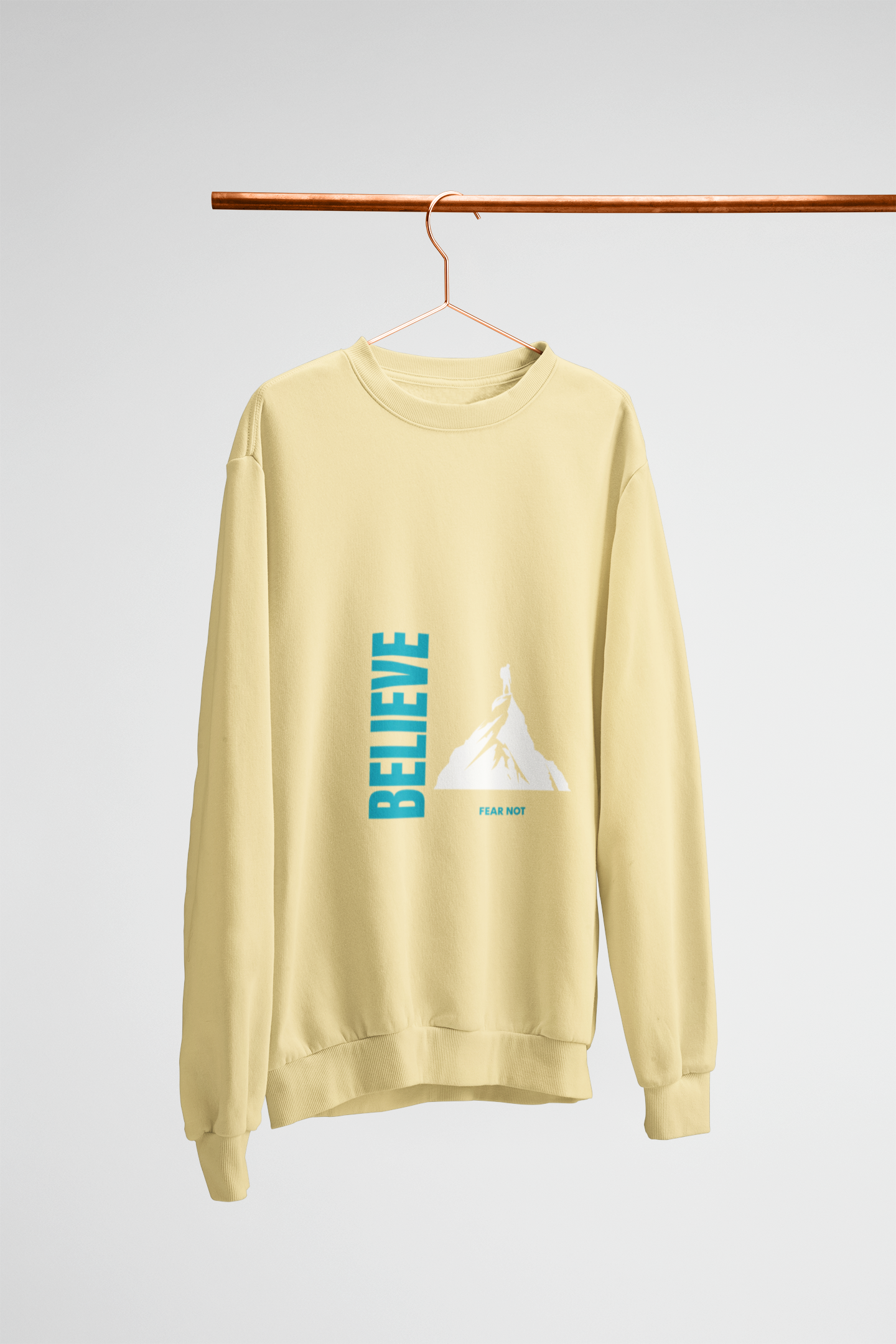 Yellow sweatshirt with 'BELIEVE' graphic on a hanger against a light white background