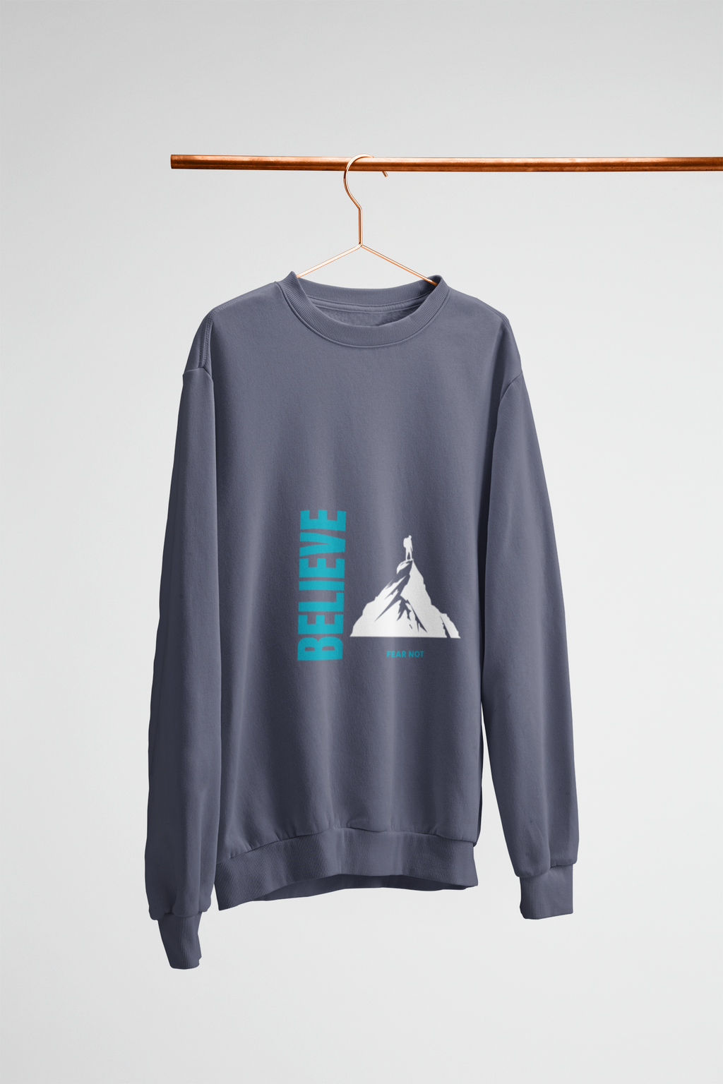 denim blue sweatshirt with 'BELIEVE' graphic on a hanger against a light white background