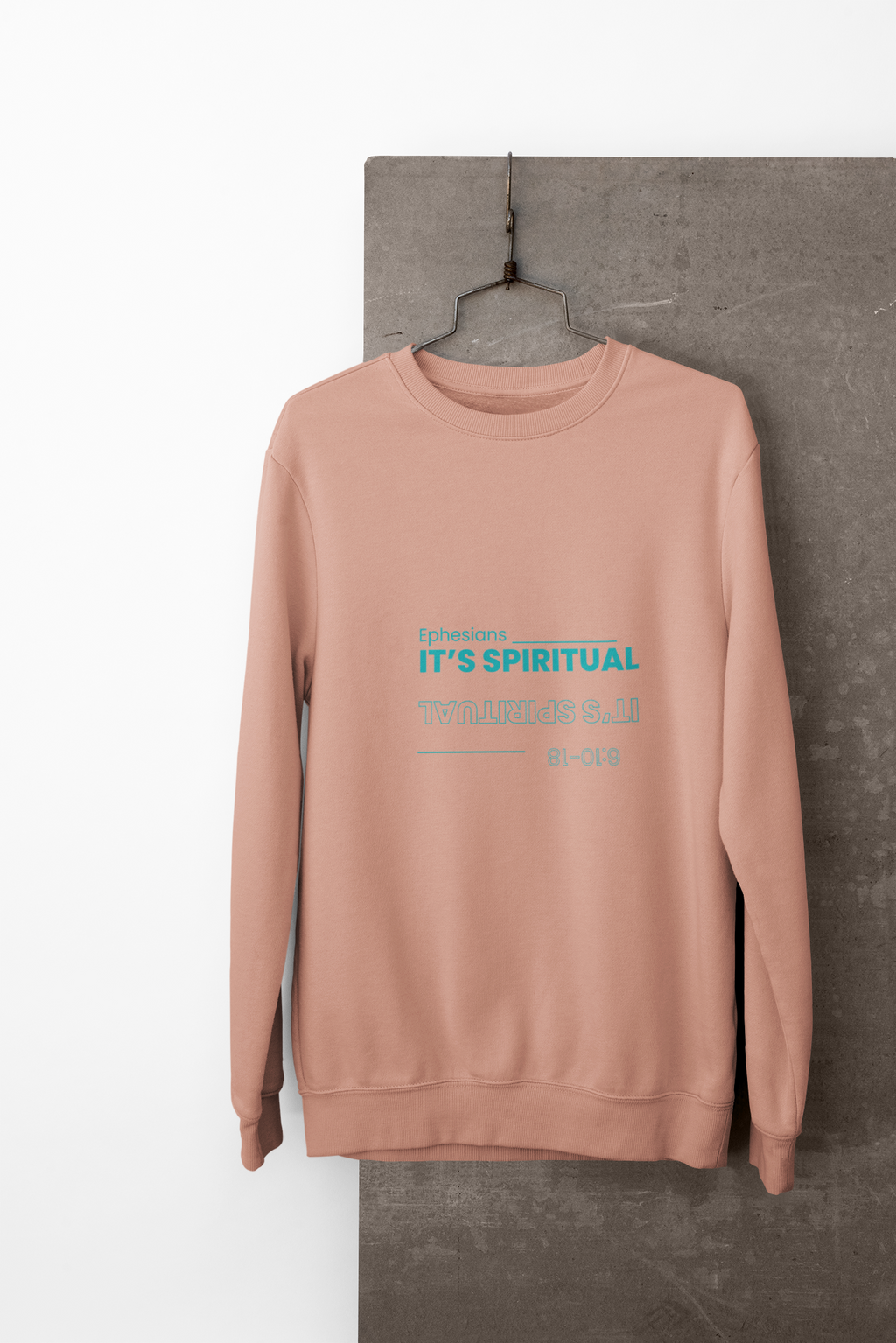 coral sweatshirt with text on a hanger against a gray wall.