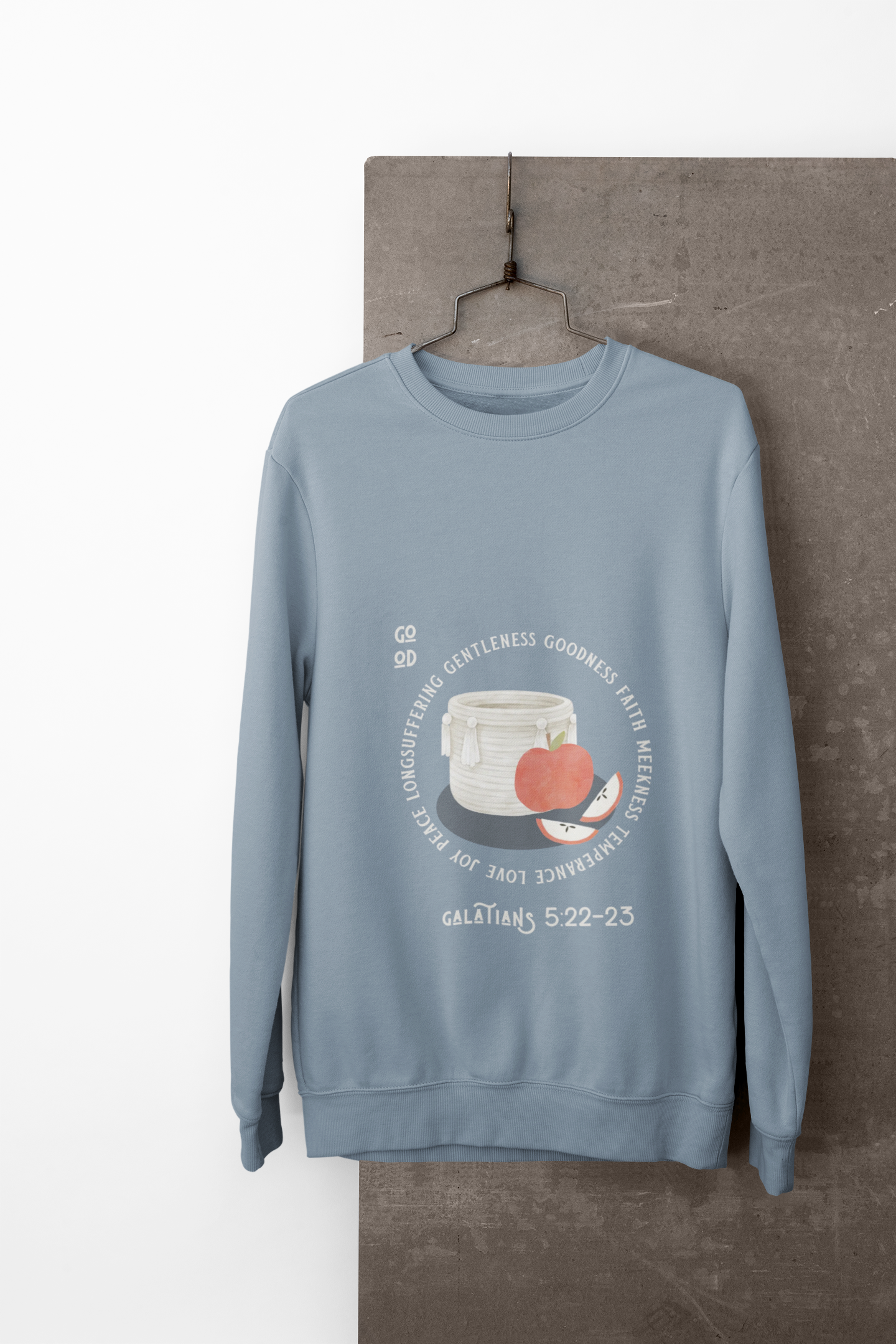 Blue sweatshirt with a graphic design on a hanger against a neutral background