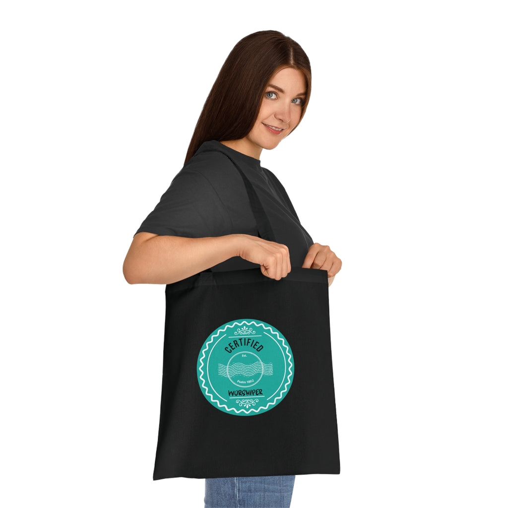 Woman holding a black tote bag with a green logo on a white background