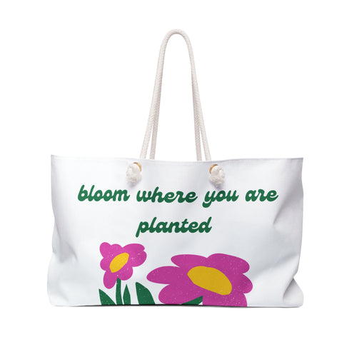White tote bag with pink flowers and green text on a white background
