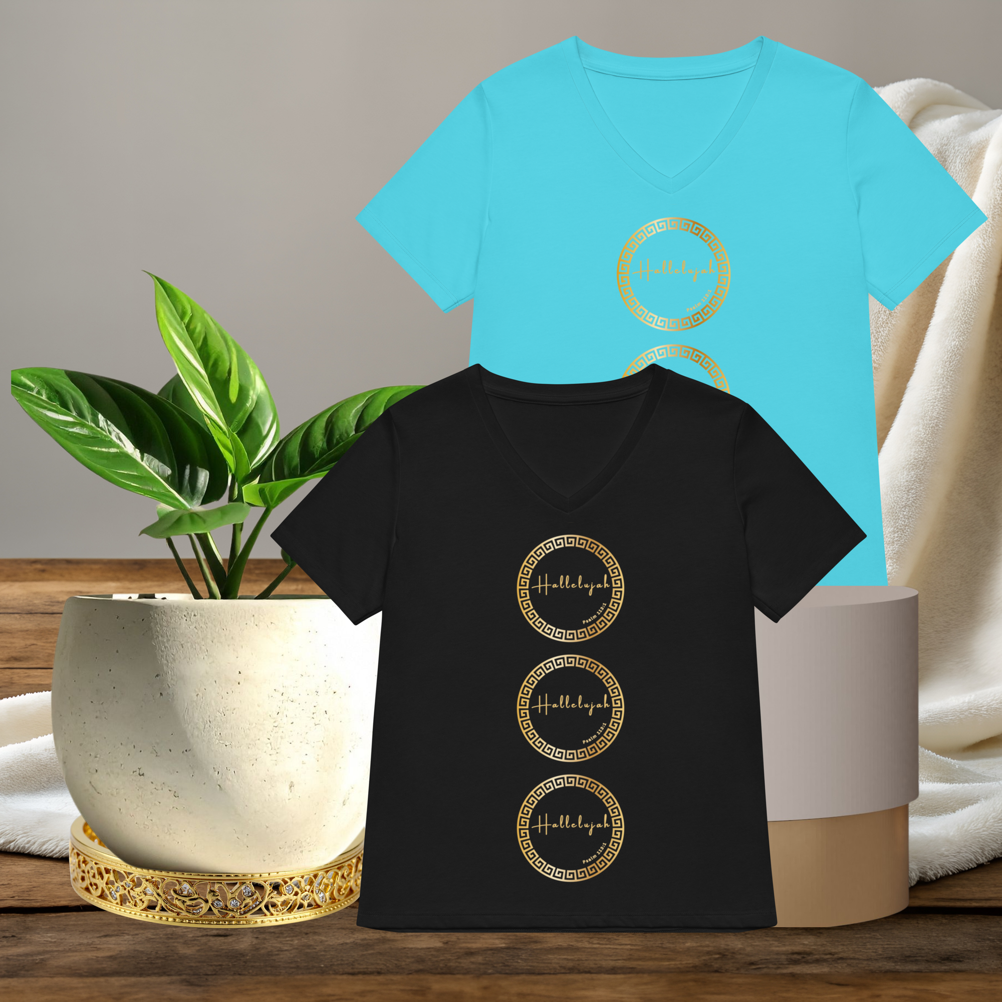Black and blue t-shirts with gold circular designs on a wooden surface with plants.