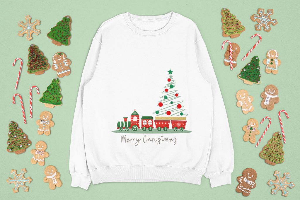 White sweatshirt with Christmas tree and train design on a green background with festive cookies and candy canes.
