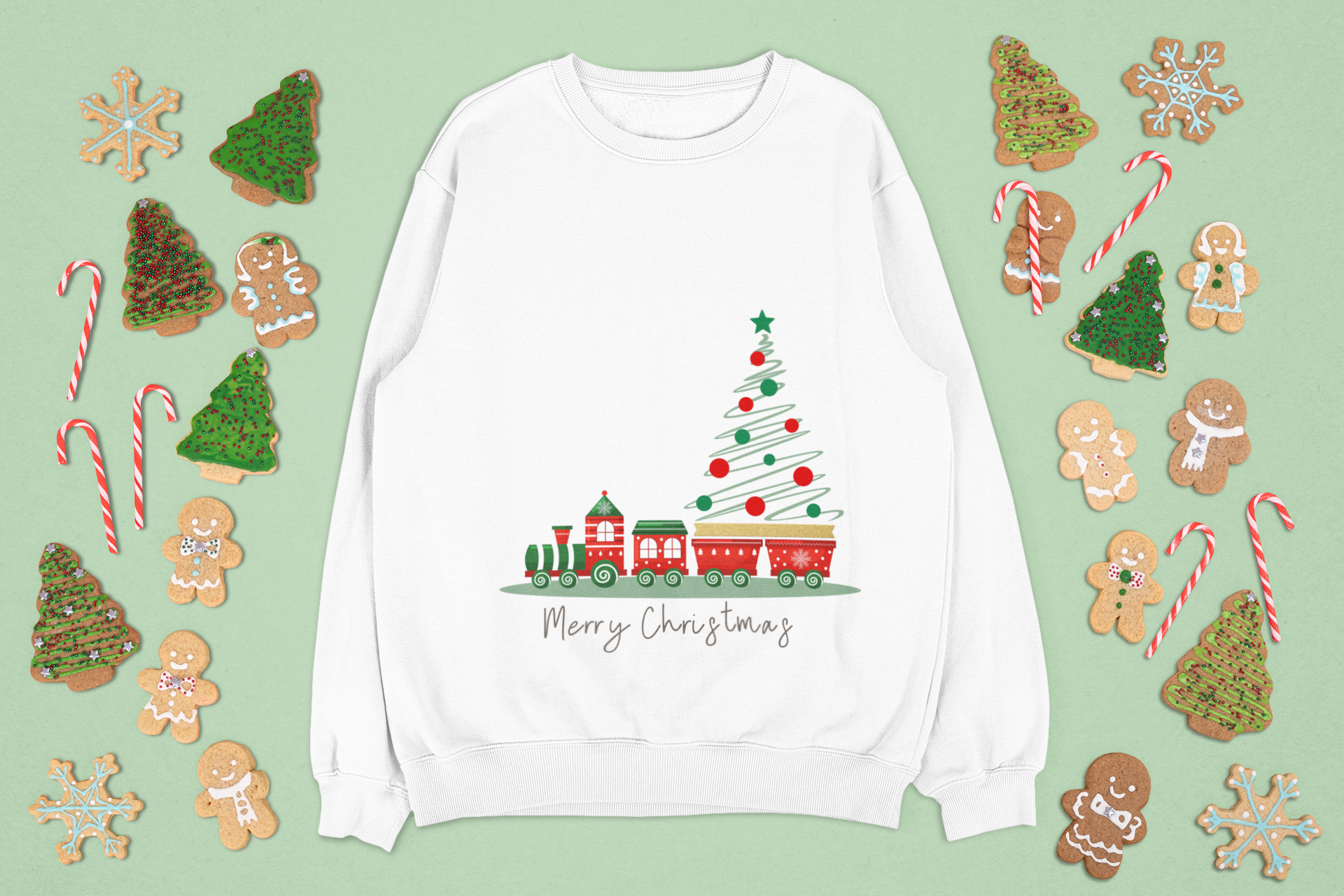 White sweatshirt with Christmas tree and train design on a green background with festive cookies and candy canes.