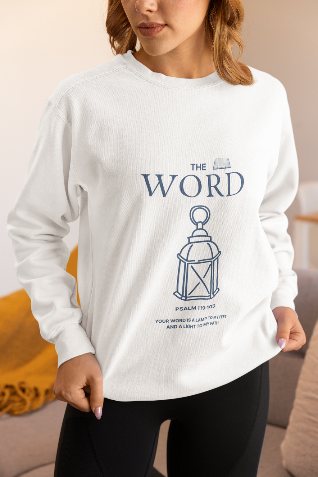 person wearing white sweatshirt with blue letters "The Word" Psalm 119:105 and lantern.