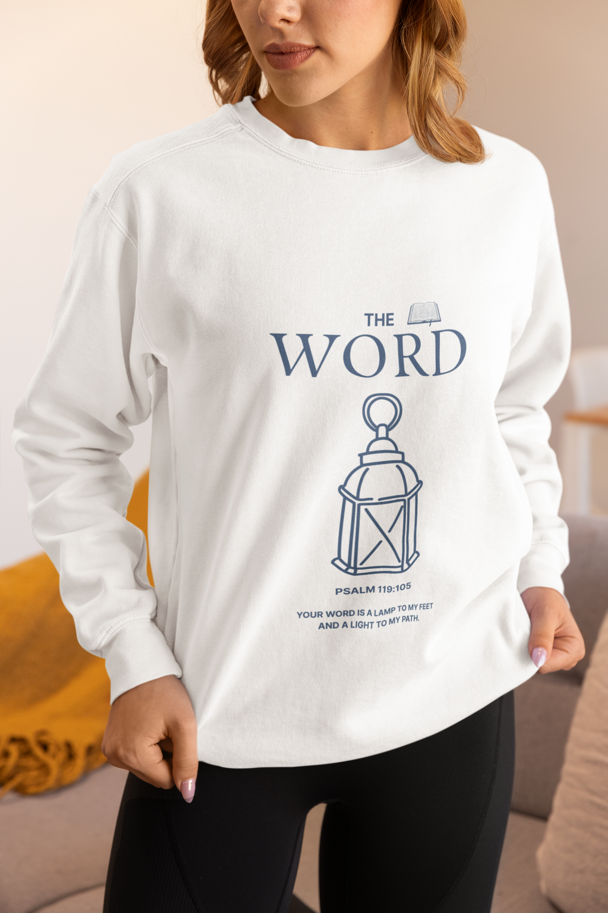 person wearing white sweatshirt with blue letters "The Word" Psalm 119:105 and lantern.
