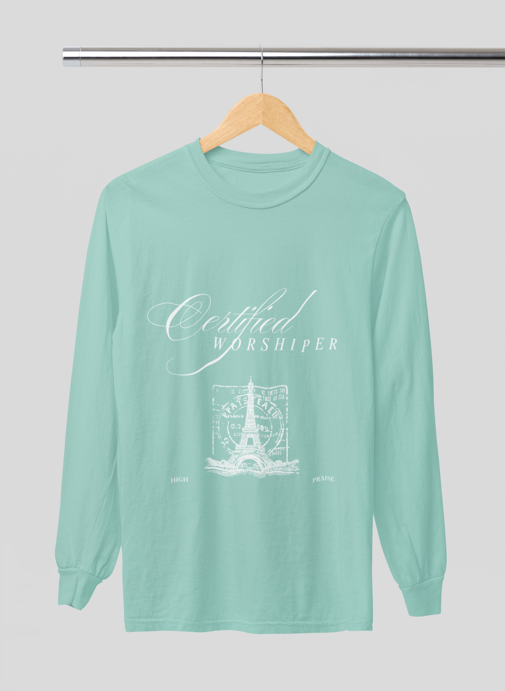 Mint green long-sleeve shirt with 'Certified Worshipper' text on a hanger against a light gray background