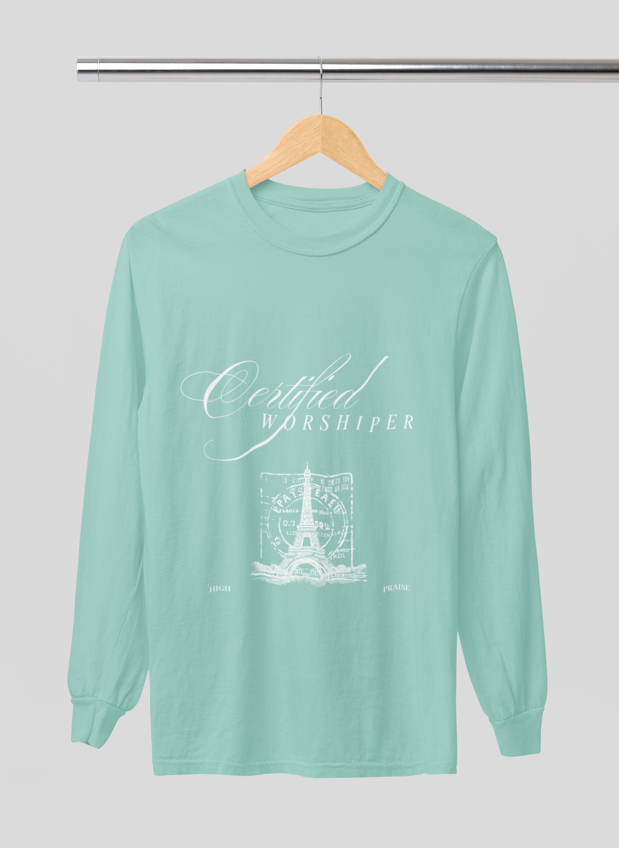 Mint green long-sleeve shirt with 'Certified Worshipper' text on a hanger against a light gray background