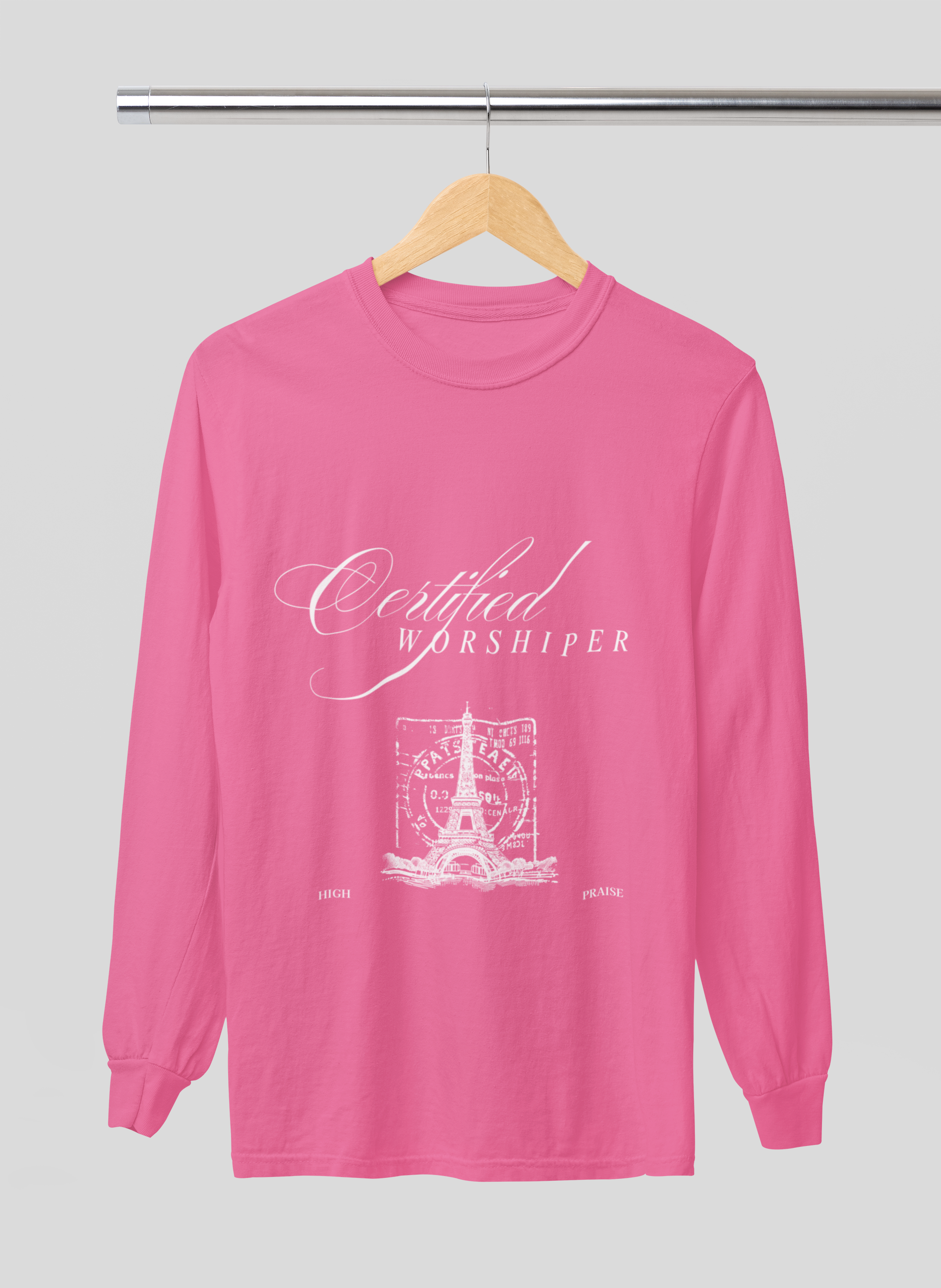 Pink long-sleeve shirt with 'Certified Worshipper' text on a hanger against a gray background