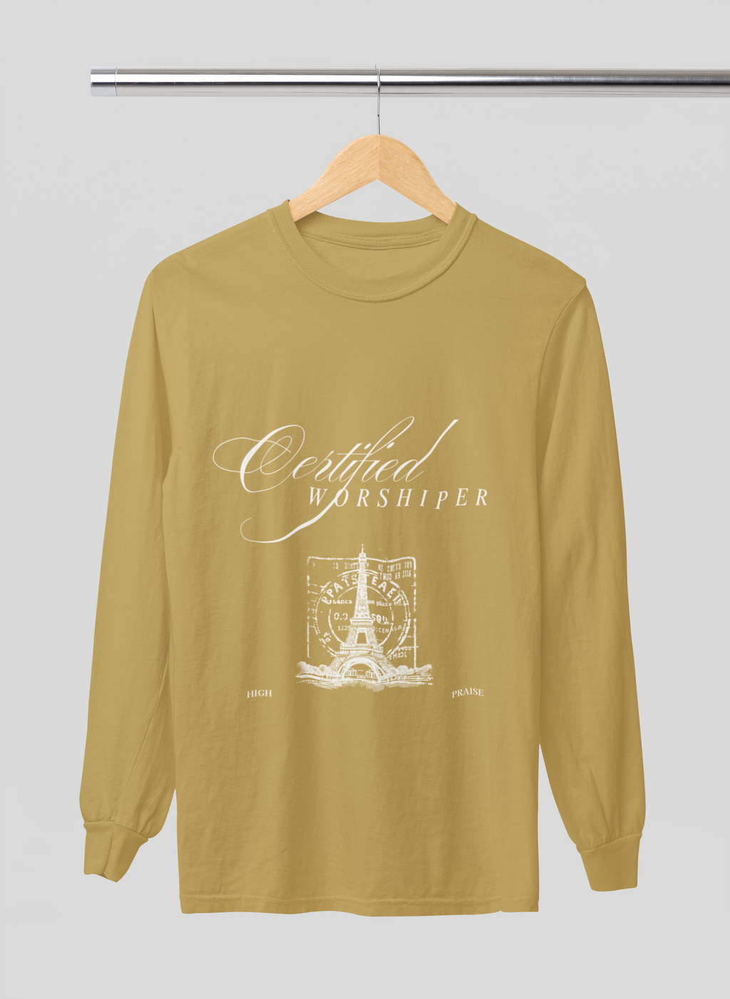Mustard yellow long-sleeve shirt with 'Certified Worshipper' text and graphic on a hanger against a light gray background