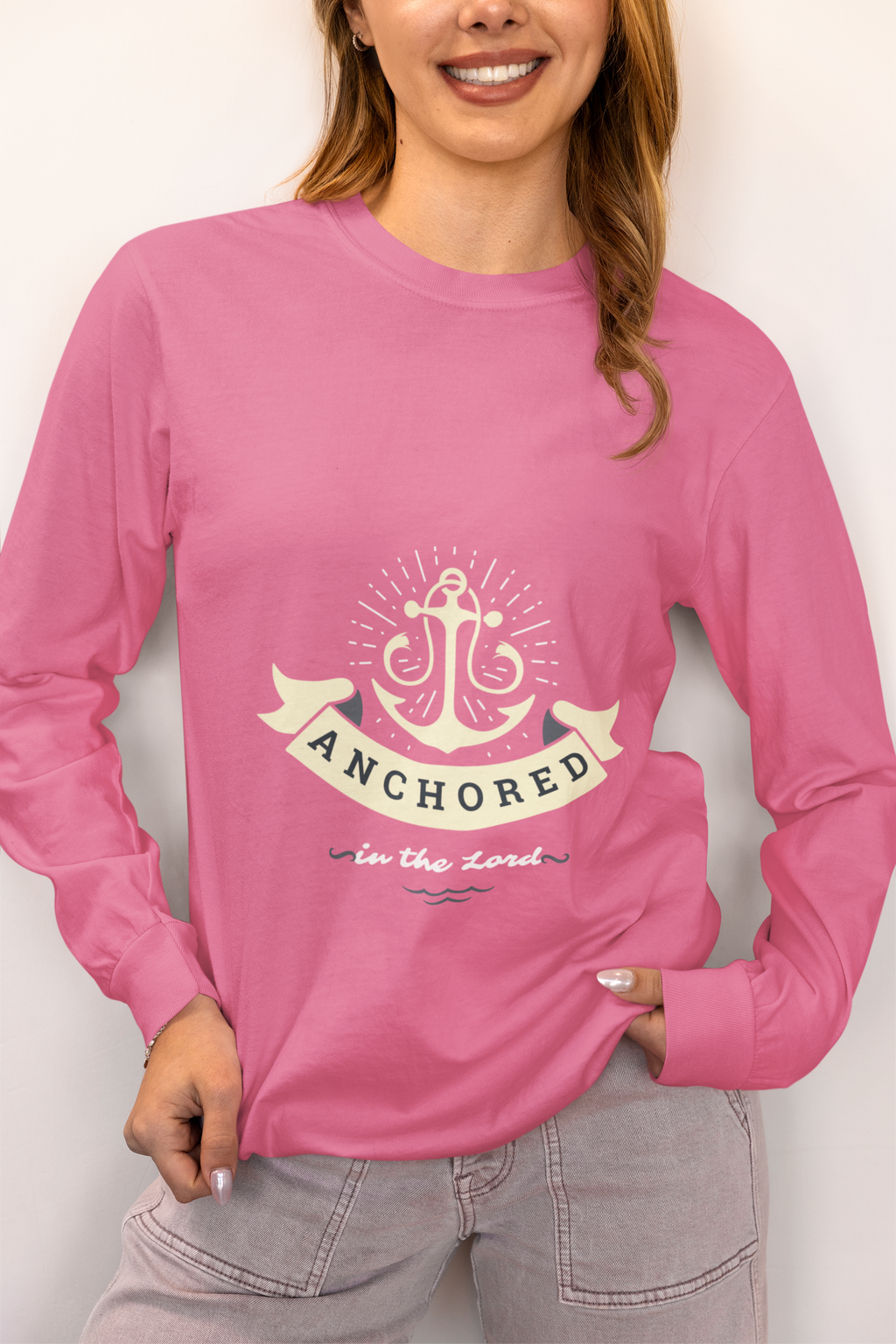 Person wearing a pink long-sleeve shirt with an anchor design and text.